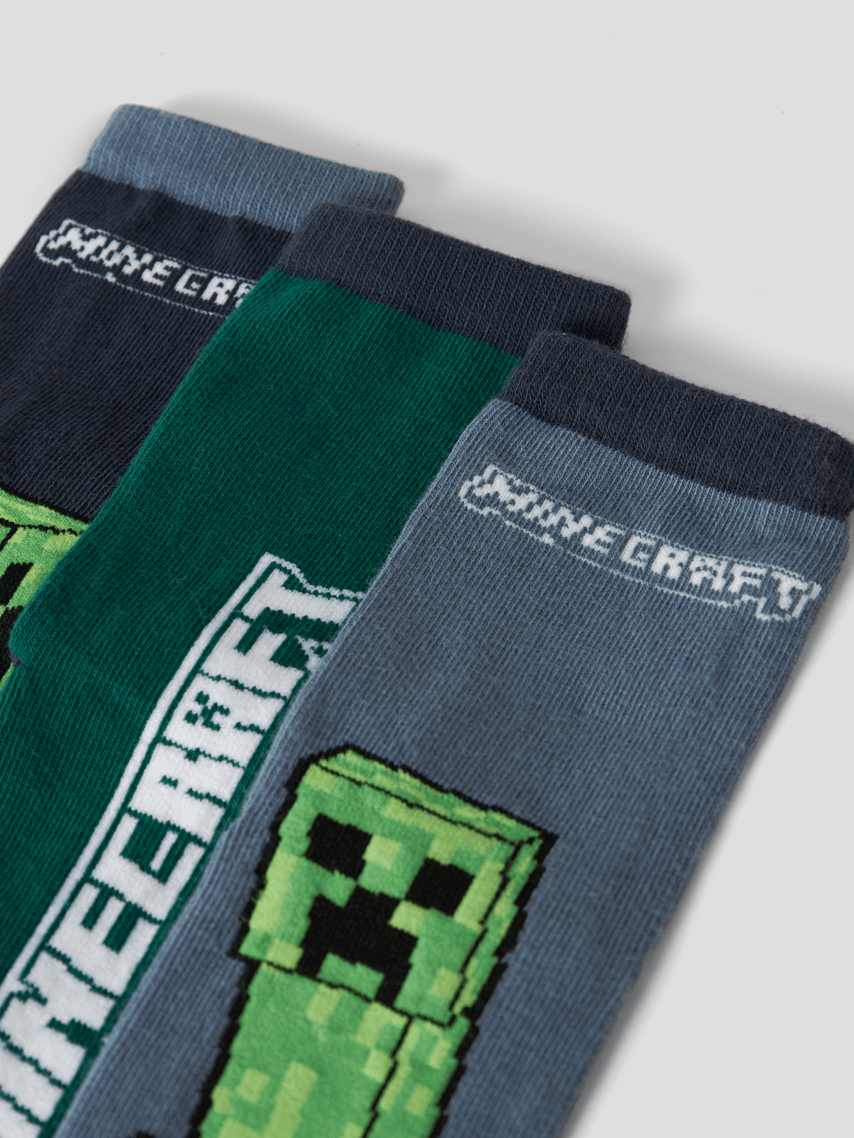 Nærbilde av tre Minecraft-sokker med Creeper og logo