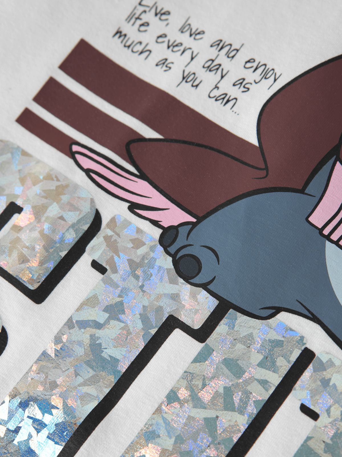 Nærbilde av glitrende sølvtrykk og Stitch-motiv på t-skjorten