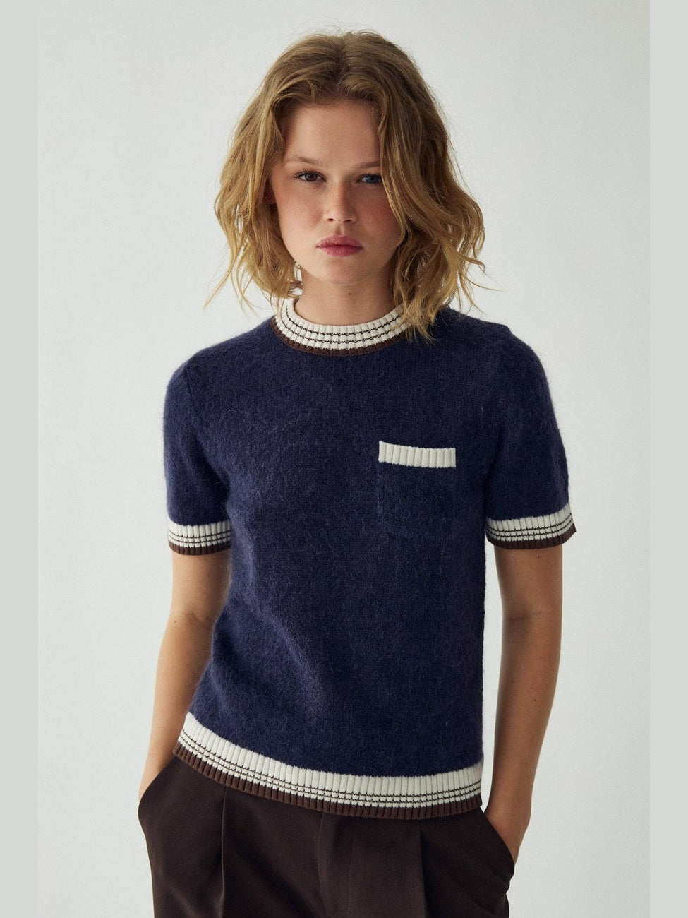 Modell med marineblå Marthy strikkegenser med korte ermer og brystlomme.