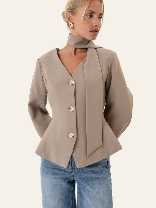 Lys brun blazer på modell med det løse knytebåndet rundt halsen